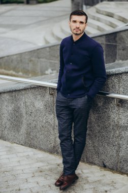 Korkulukların yanında gözlüklü genç bir adam.