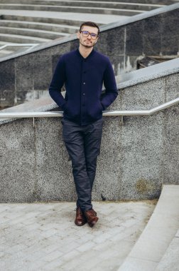 Korkulukların yanında gözlüklü genç bir adam.