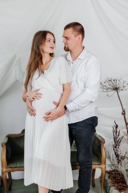 Hamile bir kız ve kocası kucaklaşırlar.