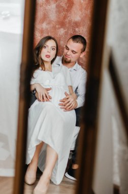 pregnant woman with her husband in the mirror