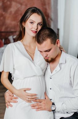 a pregnant girl sits on a man's lap