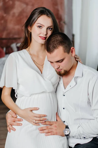a pregnant girl sits on a man\'s lap