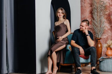 Hamile bir kadın ve bir adam sandalyede oturuyorlar.