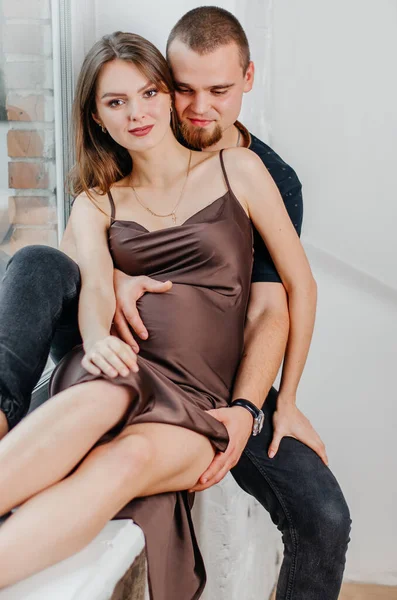 男と妊婦が窓辺に座って抱き合っている — ストック写真