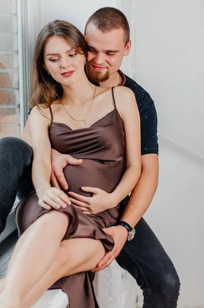 Hombre Una Mujer Embarazada Están Sentados Alféizar Ventana Abrazándose — Foto de Stock