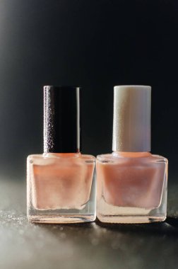 Masada yan yana duran iki şişe pembe oje.