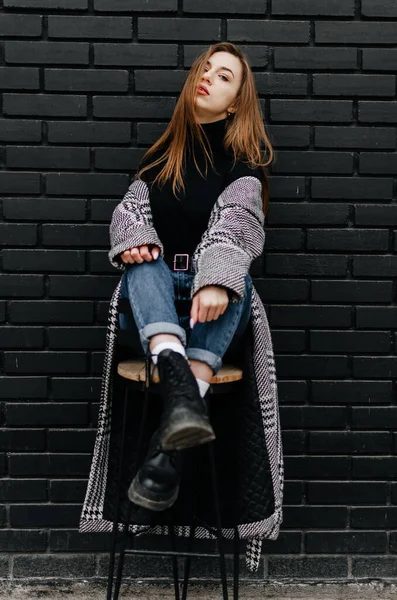 Girl Gray Coat Sits Chair Black Wall — Stock Photo, Image