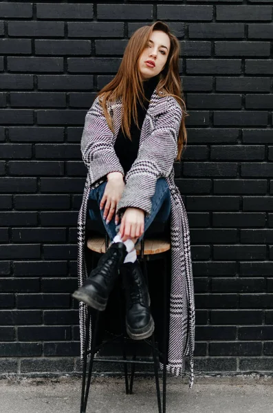 Girl Gray Coat Sits Chair Black Wall — Stock Photo, Image