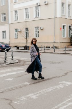 Palto ve kotla karşıdan karşıya geçen bir kadın.