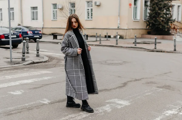 stock image A woman crossing the street in a coat and jeans