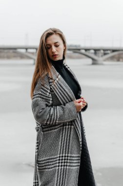 Donmuş bir nehrin kenarında bir kadın duruyor.