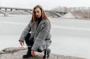 Donmuş bir nehrin kenarında bir kadın duruyor.