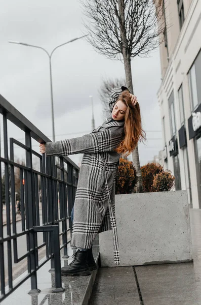 stock image a girl in a gray coat and jeans holds on to the handrail