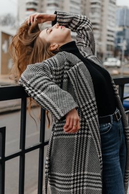 Kız korkuluklara yaslanıyor.