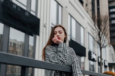 Kız binanın yanındaki korkuluklara dayanıyor.