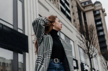 Bir binanın arka planında ceketli bir kız.