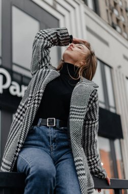 Bir binanın arka planında ceketli bir kız.