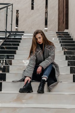 Ceketli bir kız merdivenlerde oturuyor.