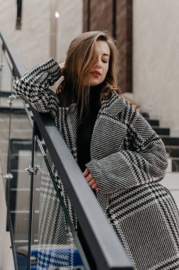 Kız merdivenlerin yanındaki korkuluklara tutunuyor.