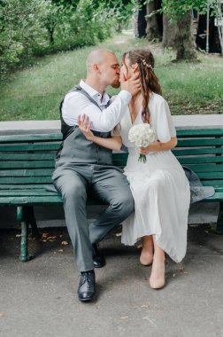 Gelin ve damat bir bankta otururken öpüşürler.