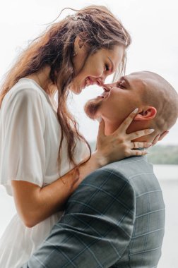 Gelin ve damat sarılıyor ve gülümsüyor.