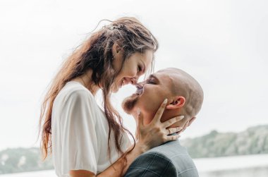 Gelin ve damat sarılıyor ve gülümsüyor.