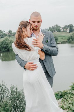 Gelin ve damat gölün arka planında kucaklaşıyor.