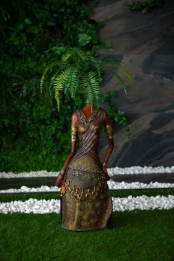 a female statue with a plant in her hair stands in a garden