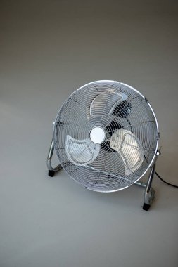 Üzerinde siyah kablo olan bir vantilatör beyaz bir yüzeye oturur.