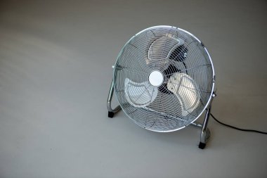 Üzerinde siyah kablo olan bir vantilatör beyaz bir yüzeye oturur.