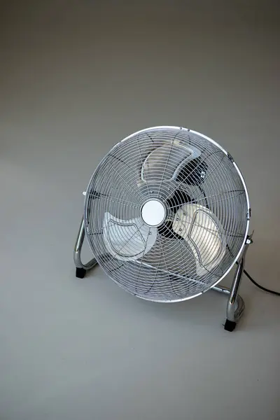 Stock image a fan with a black cord on it sits on a white surface