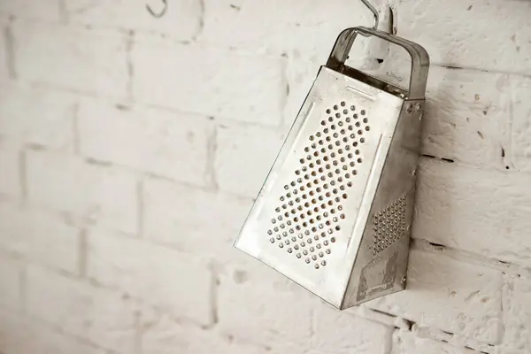 stock image a kitchen grater hangs on a white wall