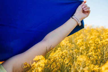 a girl with a flag of Ukraine on her shoulders, standing in a yellow field clipart