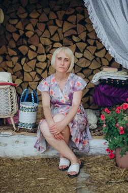 Kırsal bir dekoru olan Hasır ve çiçeklerle oturan bir kadın