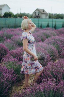 Çiçek açan tarlada lavanta buketi tutan zarif kadın.