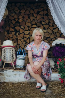 Kırsal bir dekoru olan Hasır ve çiçeklerle oturan bir kadın