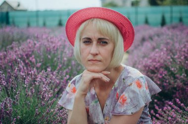 Lavanta tarlasında oturan kırmızı şapkalı bir kadın.