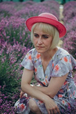 Lavanta tarlasında oturan kırmızı şapkalı bir kadın.