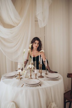 Şenlik masasında oturan zarif kadın mumlar ve çiçeklerle süslenmiş.