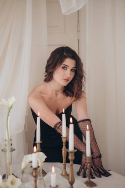 Siyah elbiseli güzel bir kadın. Zarif iç kısımda mumlarla poz veriyor.