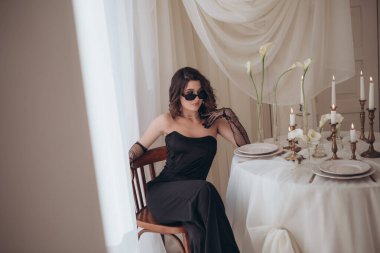 Siyah takım elbiseli kadın zarif bir sehpada.