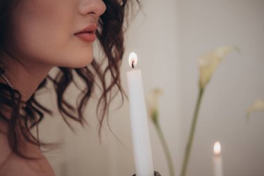 Romantik bir kadın yüzü, mum alevi ve çiçek arkaplanı.