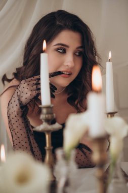 Mum ışığında çiçek ısıran kadın portresi.