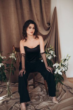 Stüdyoda zambakların arasında oturan zarif kadın.