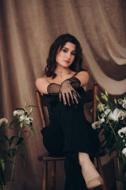 Çiçeklerle süslenmiş bağdaş kurmuş zarif bir kadın.