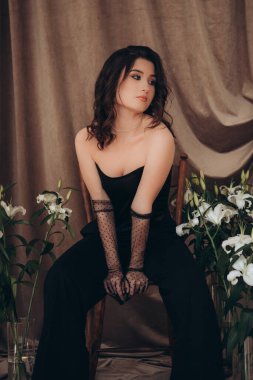 Çiçekli siyah elbiseli düşünceli bir kadın.