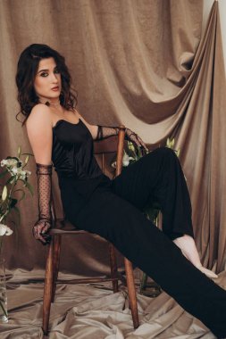 Karamsar ışıklandırma ve çiçek elementleriyle şık bir poz.