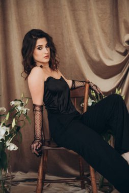 Siyahlı kendine güvenen kadın yan koltukta oturuyor.