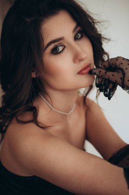 Siyah tül eldivenleri ve yumuşak ışığı olan göz alıcı bir esmer.