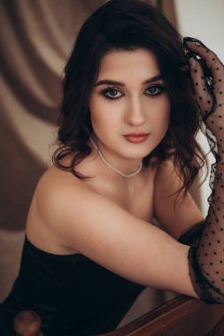 Siyah saçlı, saf eldivenli zarif bir genç kadın.